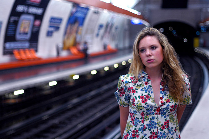 a young lady in an urban subway station poses for a pograph