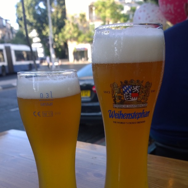 two beers sit in front of a wooden table
