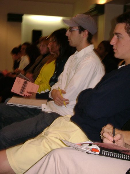 four people sitting in rows looking at papers