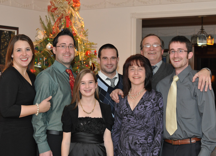 a family standing beside each other in front of a christmas tree