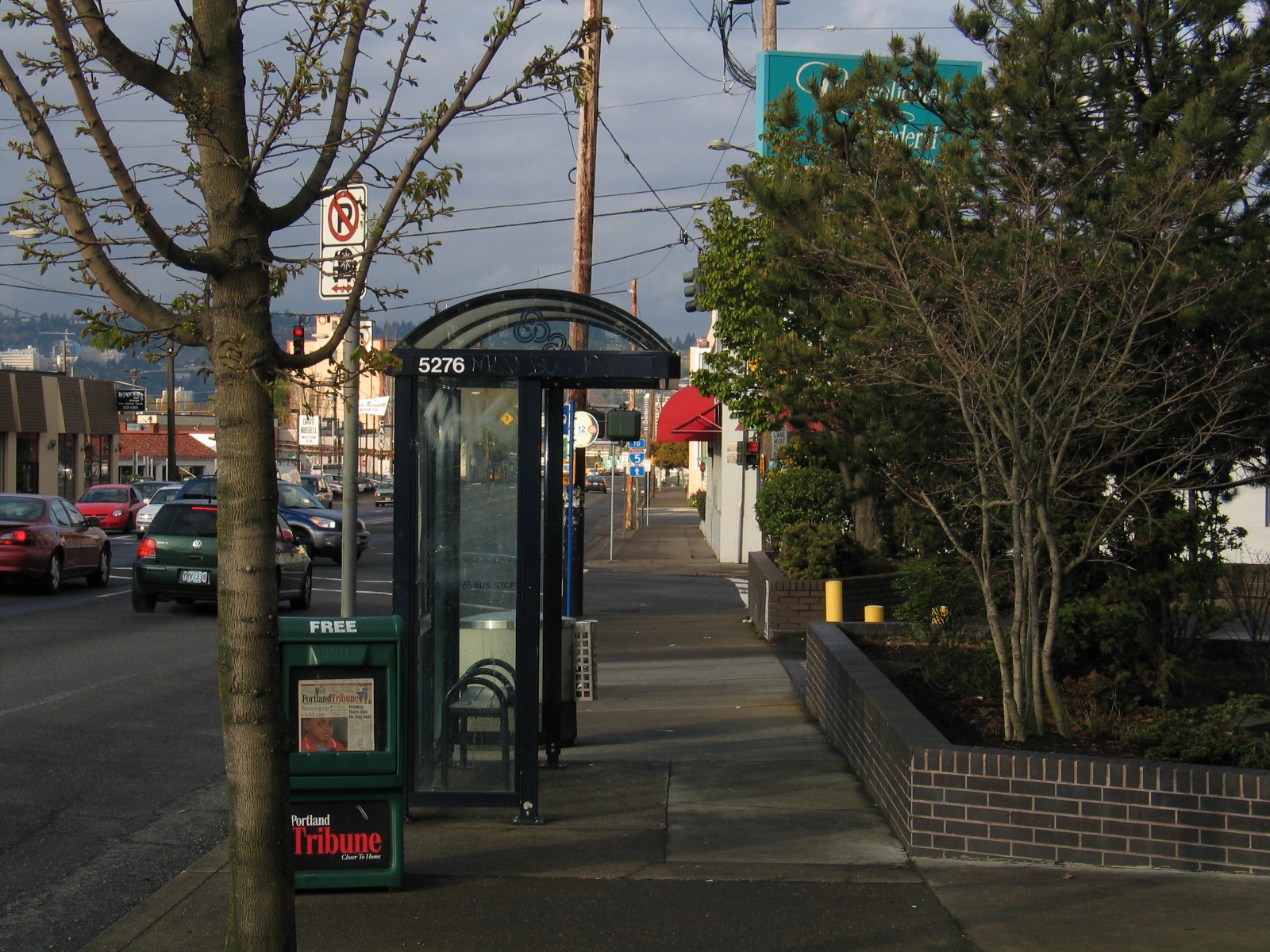 a city street has parked cars and a bus stop