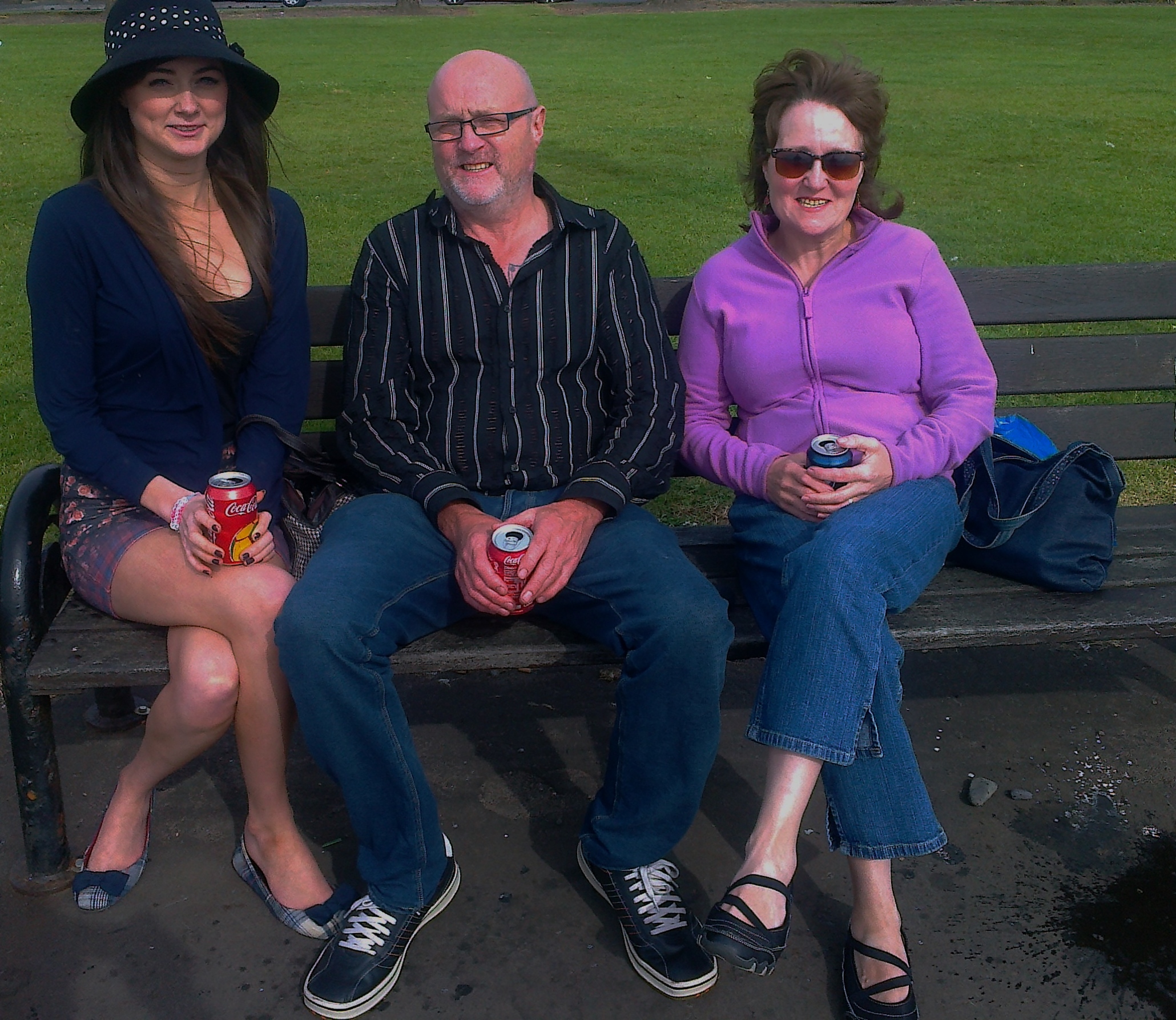 two men and a woman sitting on a bench in the park