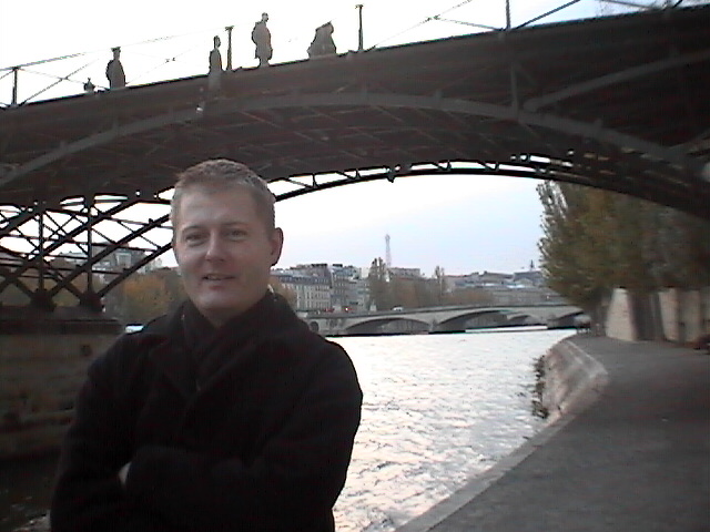 a man standing in front of a bridge on water