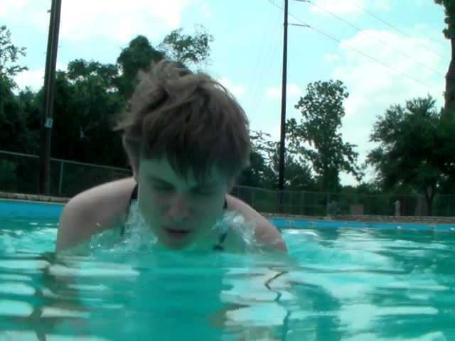 a boy in a pool of water with trees in the background