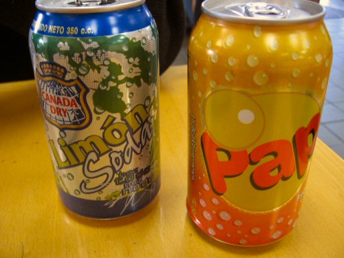 two cans of soda sitting on a yellow table