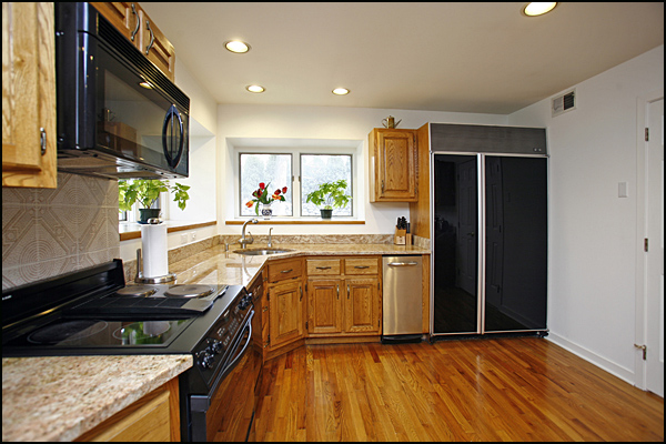the black refrigerator is next to an oven in the kitchen