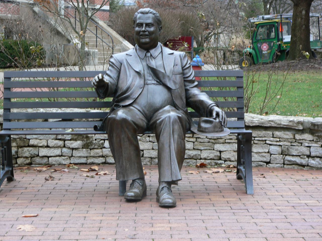 a statue of a man on a bench next to a park