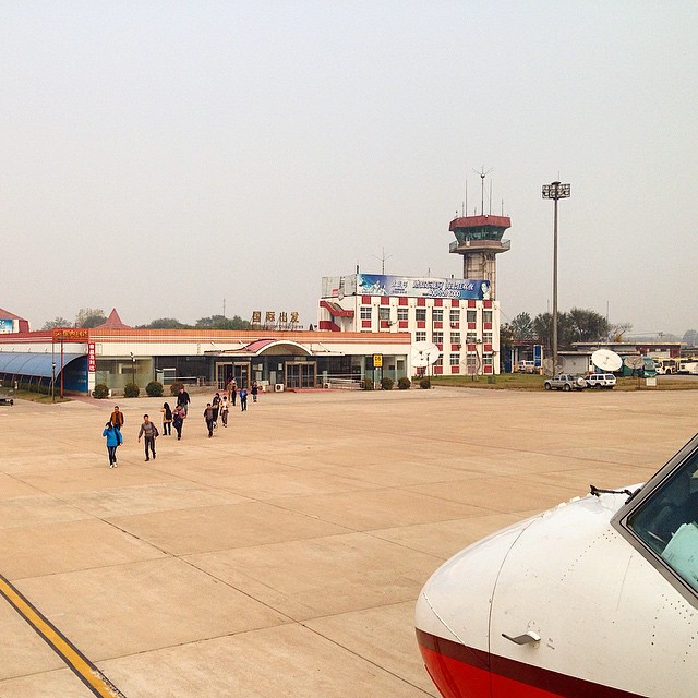 people walking towards a airport terminal with planes parked outside
