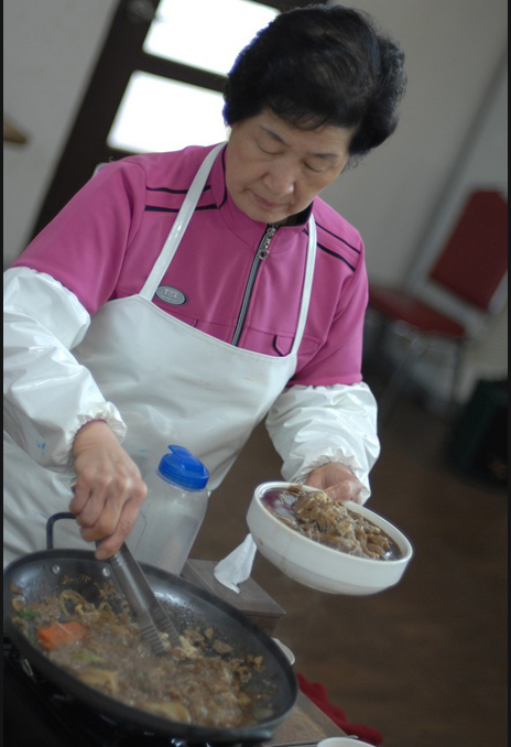 a woman cooking food from a black pot