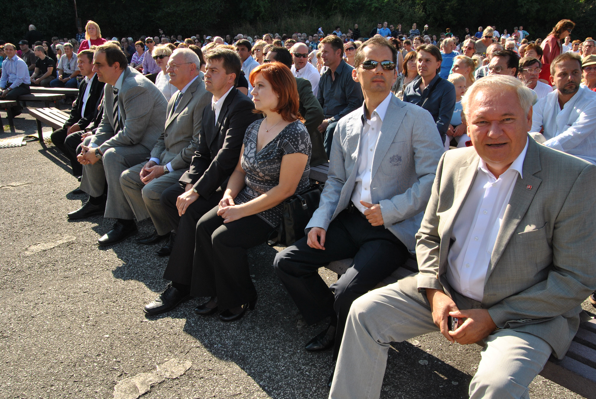 several people are seated together on the bench and one is standing