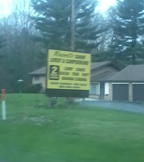 two yellow signs sitting in the grass near two houses