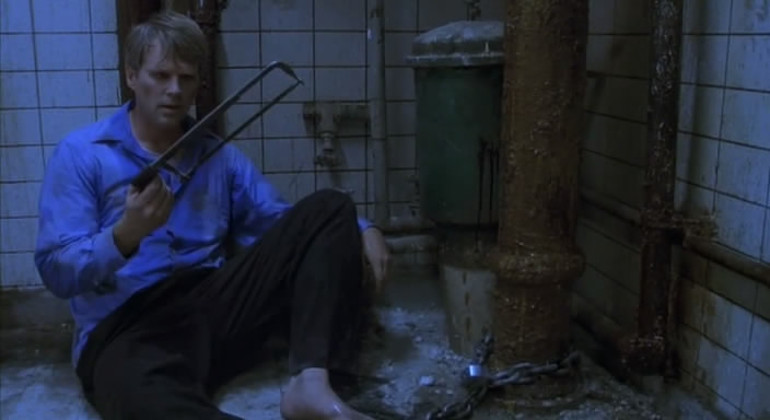 the man is sitting on the floor in front of the shower with the large gun