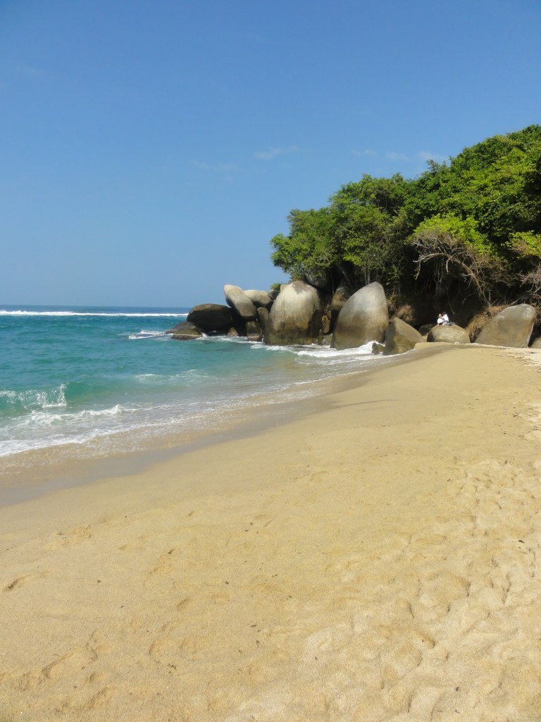 a beach with a few large rocks sitting in the sand