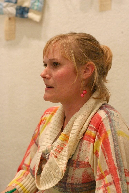 a woman with large earrings is sitting and looking into the distance