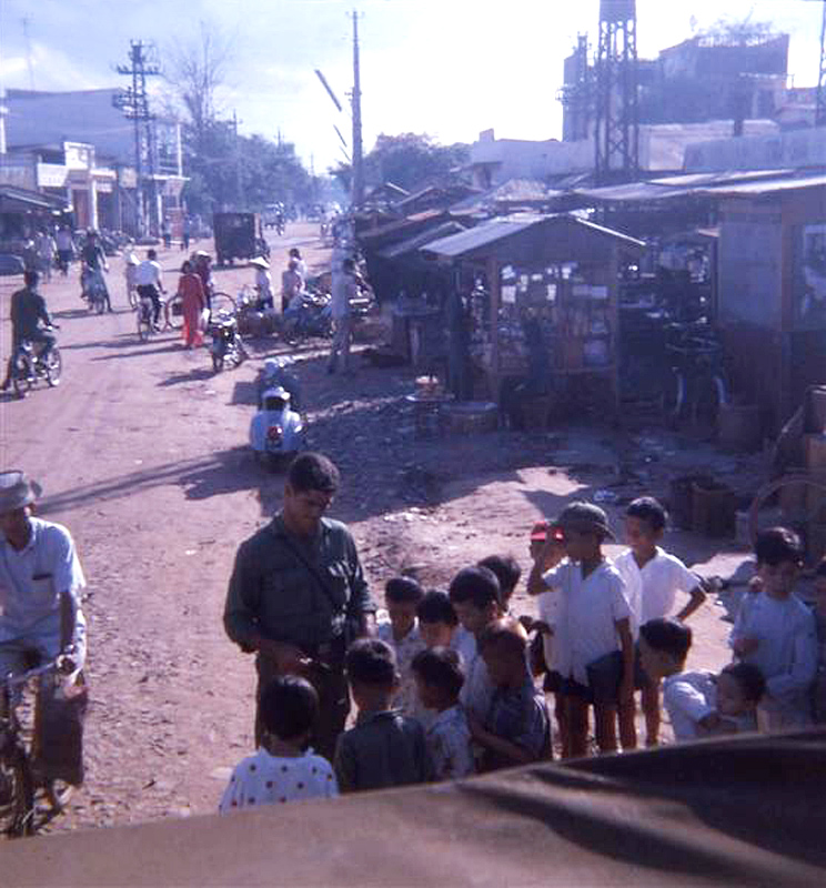 people standing in front of a shack on the side of a road