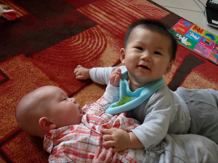 two baby babies laying next to each other on the floor