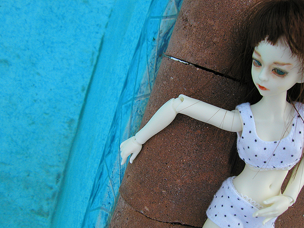 a doll with black hair laying on top of a stone wall