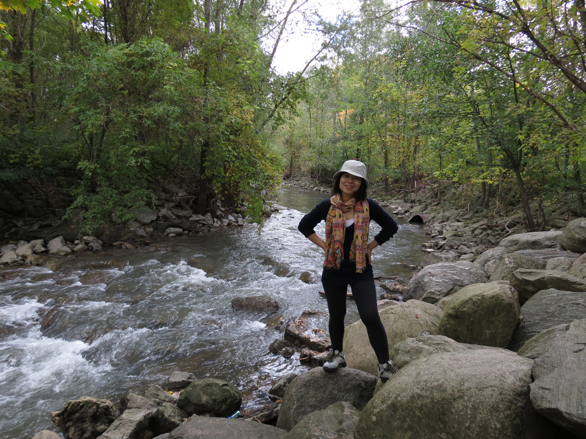 a woman stands in a rocky area by a river