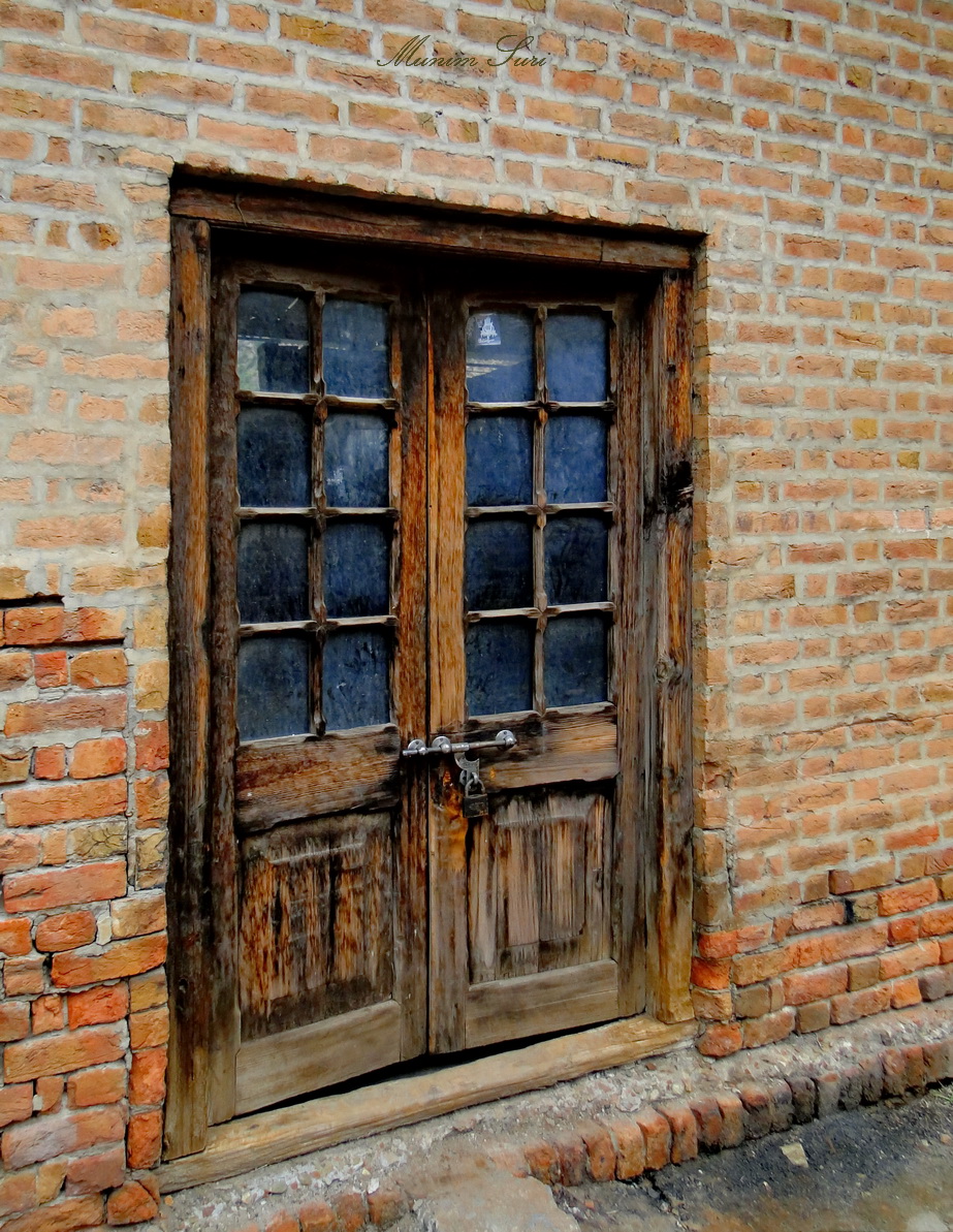 the old wooden door is painted on a brick wall