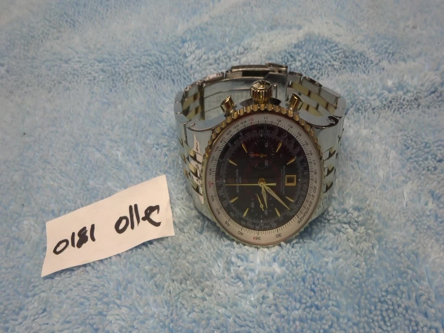 a silver and black watch with a sign in front of it that says our oil
