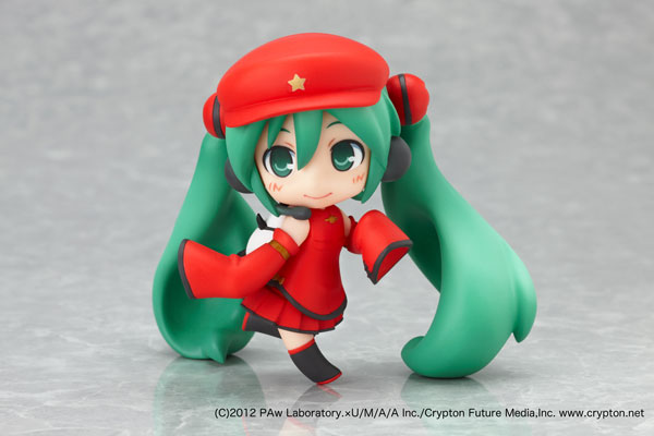 a green anime figurine, she is wearing a red hat