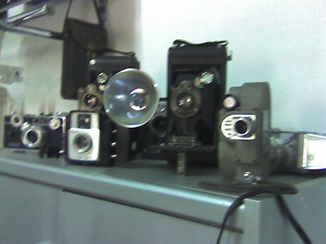 a lot of old cameras sitting on a shelf