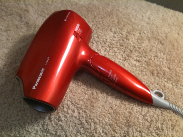 a shiny red blow dryer laying on the carpet