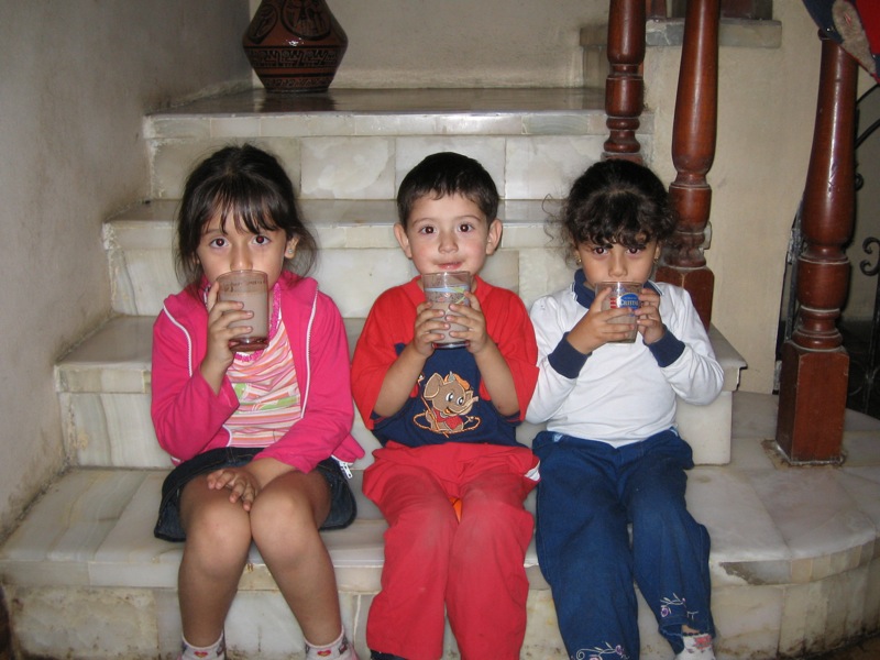 four little children sitting and drinking beverages