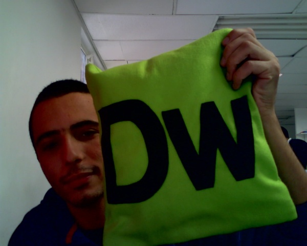 a man is holding up a pillow made of neon green fabric with the letters dw on it