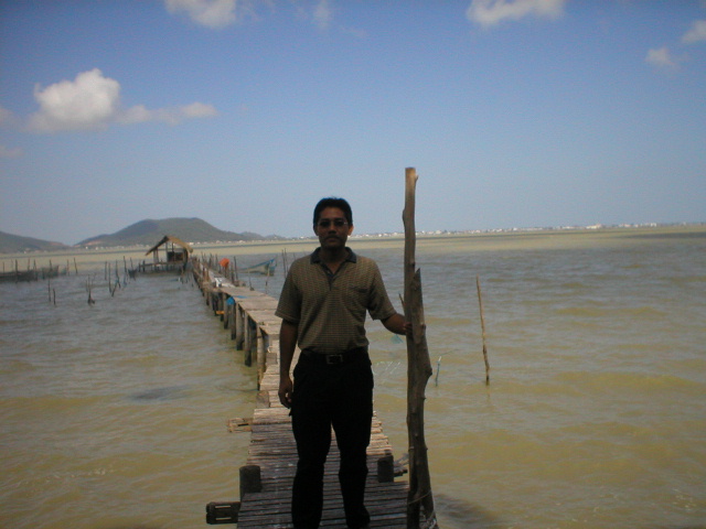a man standing on top of a long pier over looking water