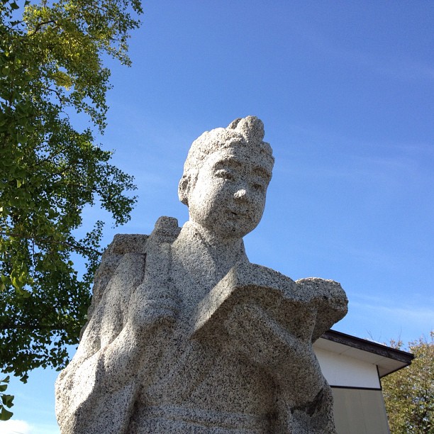 a statue of a person sitting under a tree
