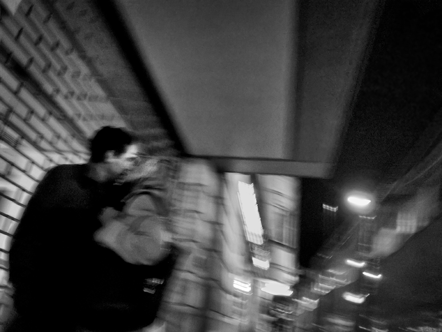 the blurry po of people and street lamps shows a man holding a woman's head