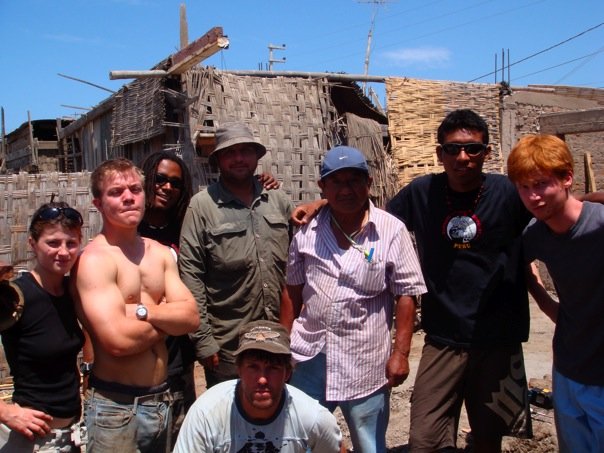 group of men posing for camera in front of an unfinished building