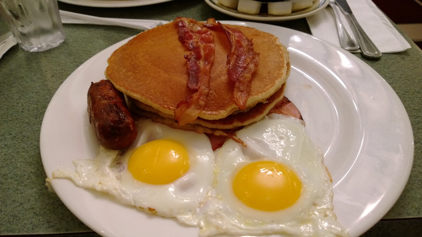 a breakfast plate contains eggs and pancakes, as well as sausage