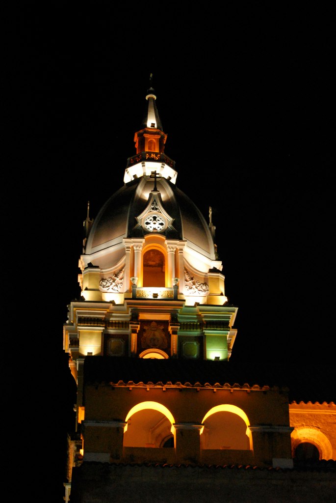 a lit up church steeple with lights and a clock at night