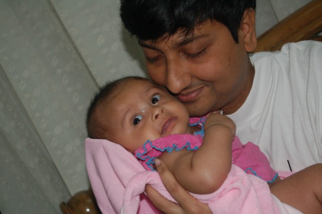 a man holding a baby while it is wearing a pink towel