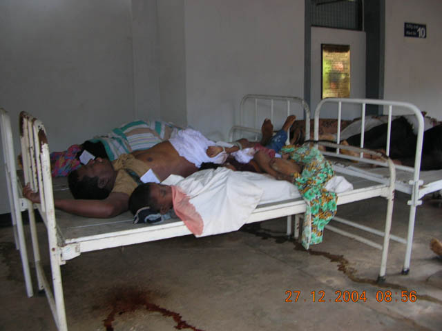 several men sleeping in a room with metal bed frames