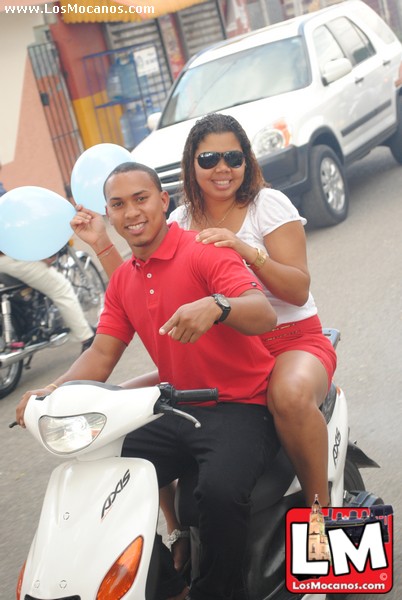 a man and woman ride a moped down the street