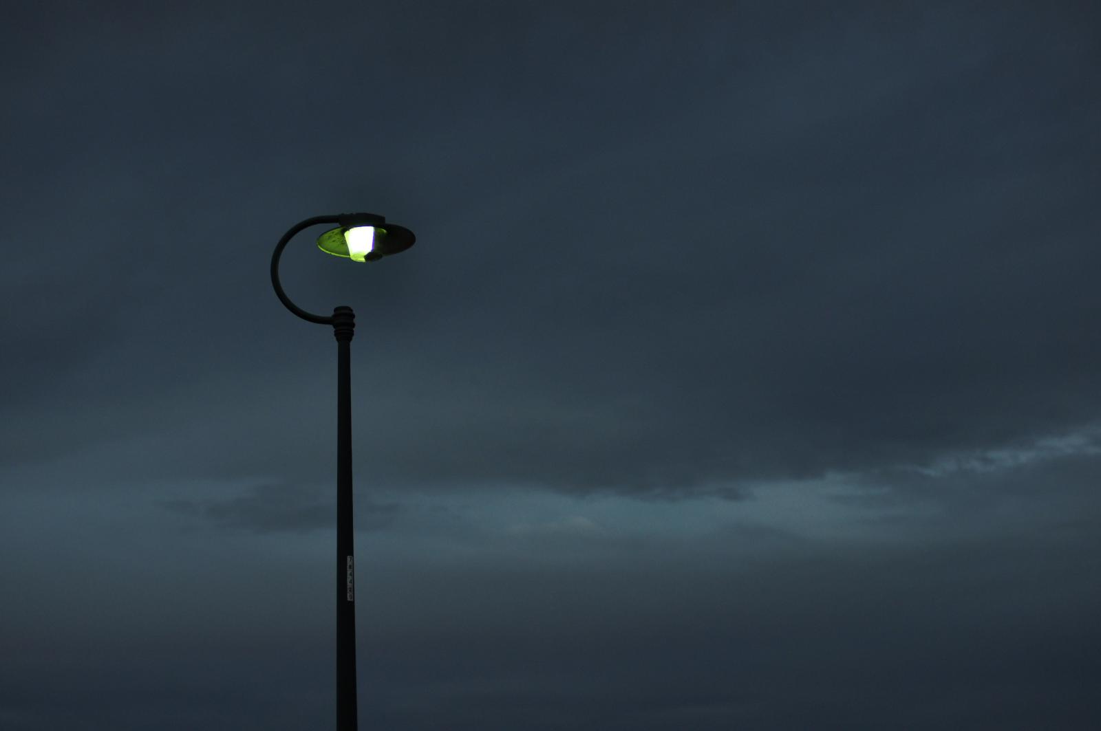 street lamp with glowing light in the middle on cloudy night sky