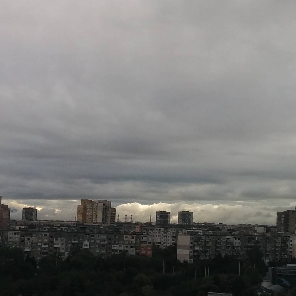 there is an overcast sky with clouds and buildings behind it