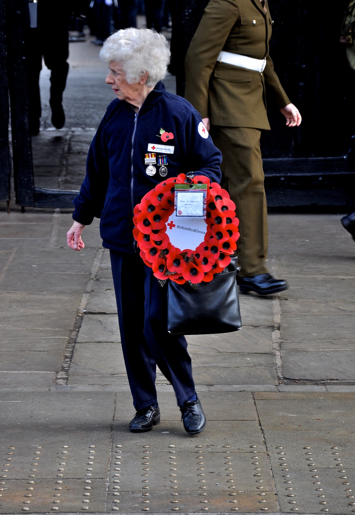 a woman walks down the sidewalk with a wreath