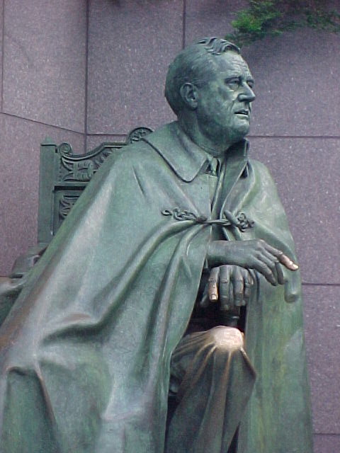 a statue of the president is sitting in a green bench