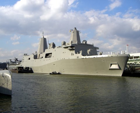 a large military ship docked in a marina