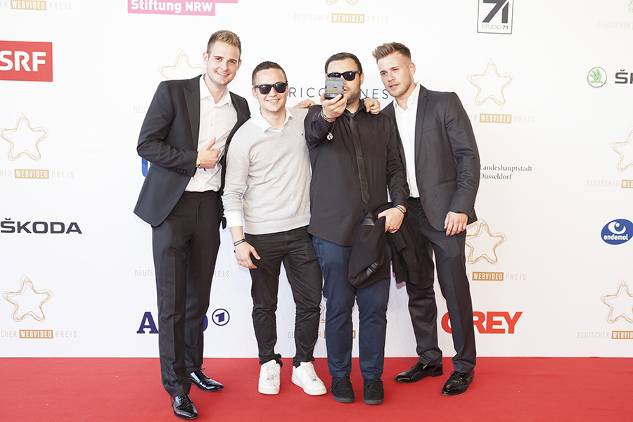 three men posing together at a red carpet event