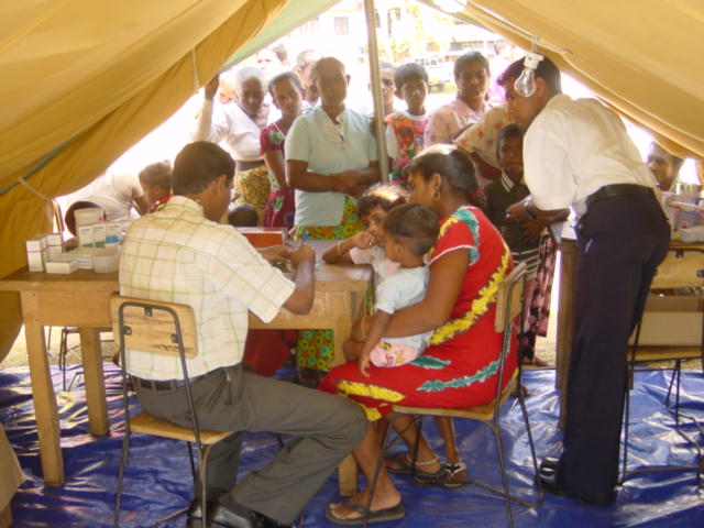 people sitting at tables under a tent