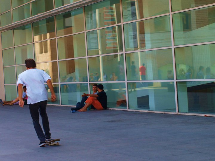 people in front of glass building sitting on skateboards