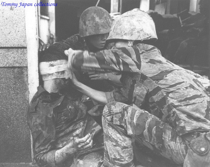 a soldier hugging another soldier while they are on the ground