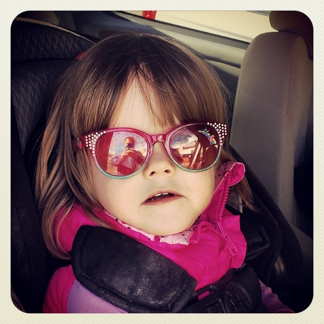 a little girl wearing sunglasses is sitting in her car seat
