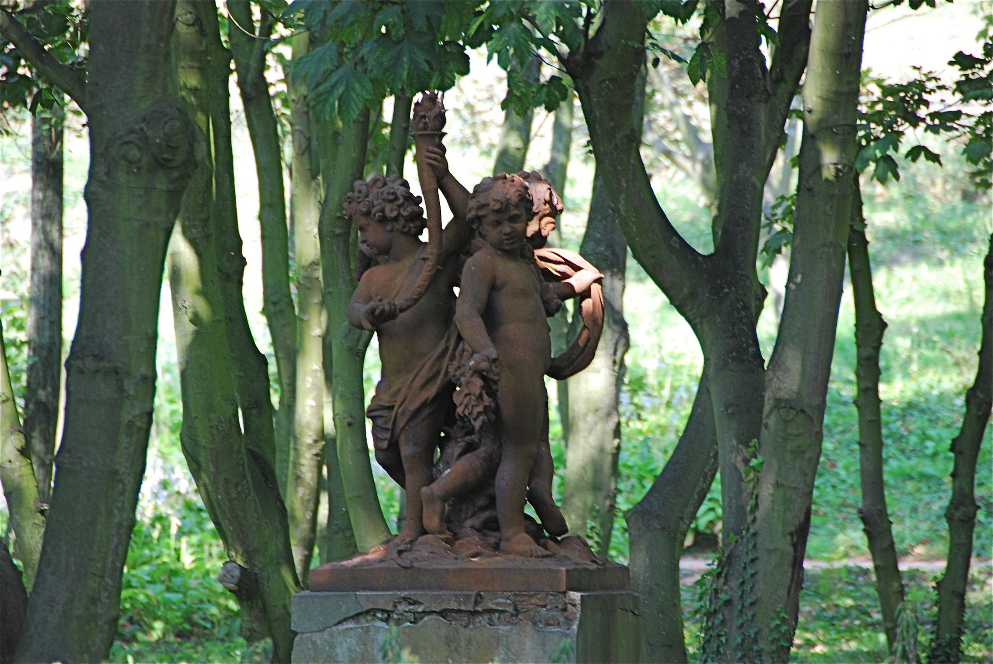 a statue stands next to trees in the woods
