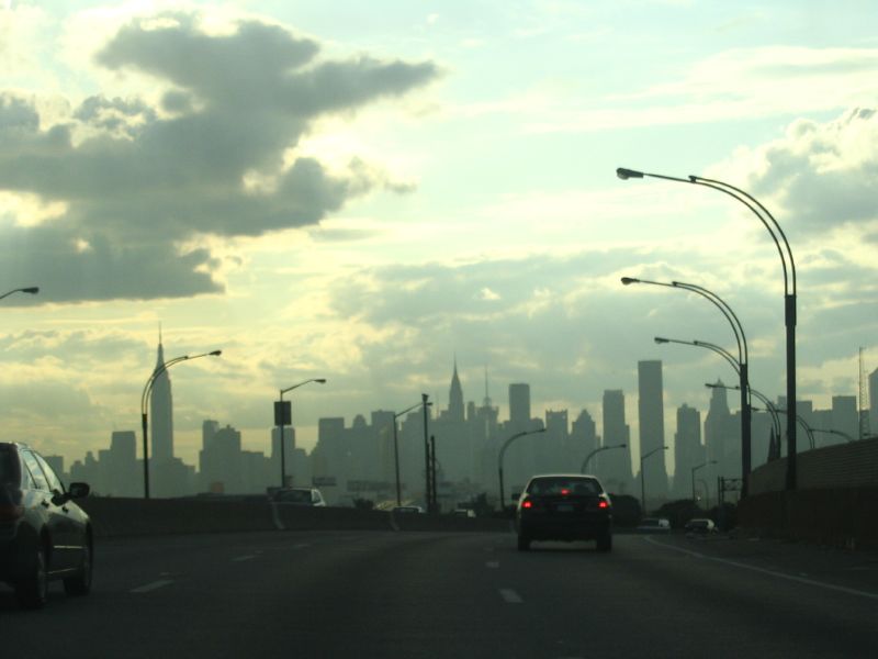 a group of cars on a street with lots of tall buildings